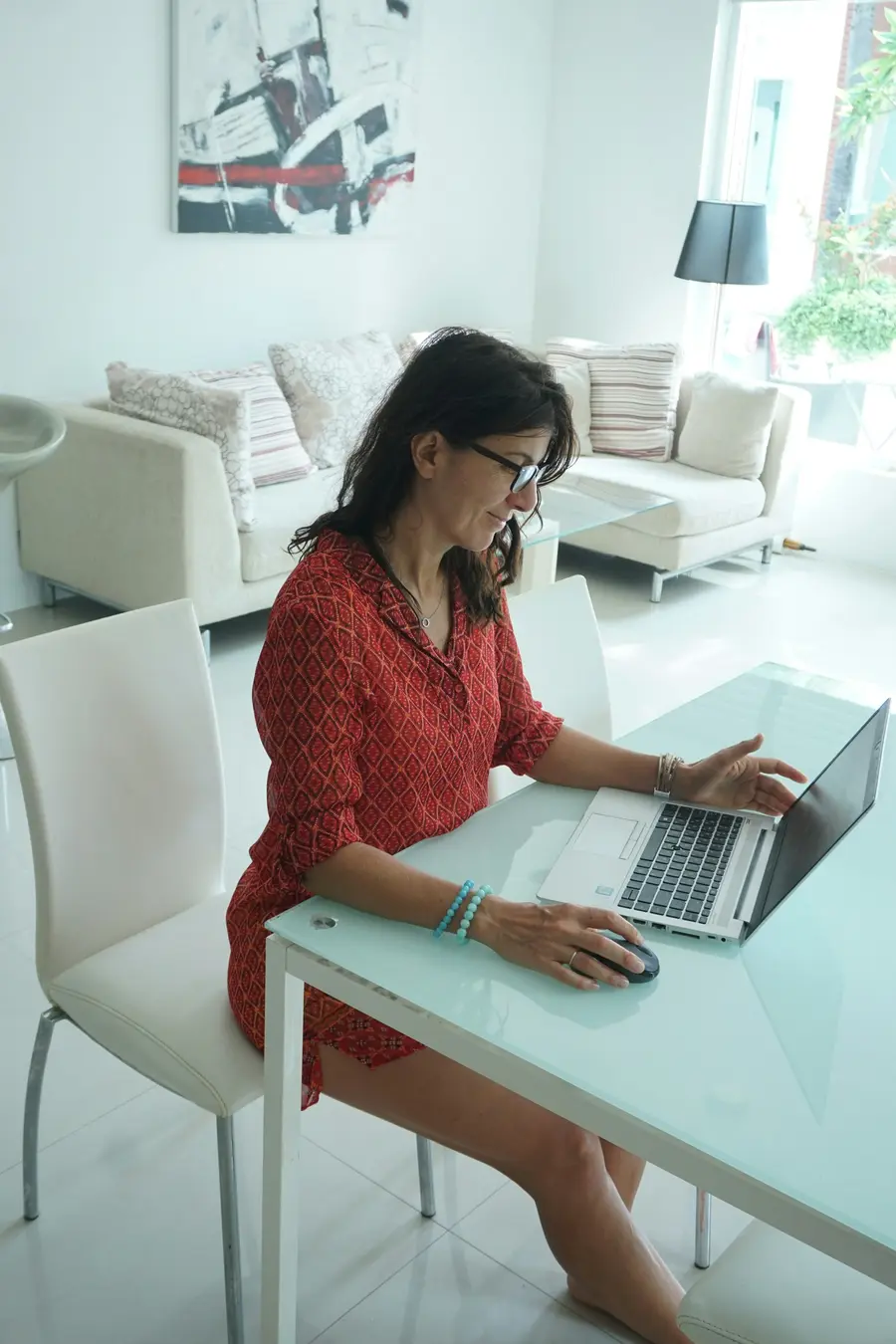 Empresária sorridente usando notebook em escritório claro com plantas e detalhes azuis