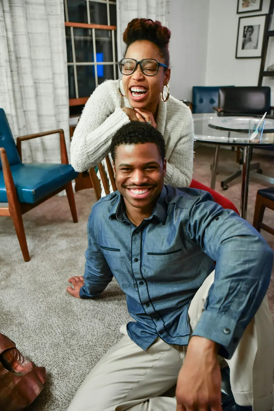 Casal sorrindo sentado no chão da sala