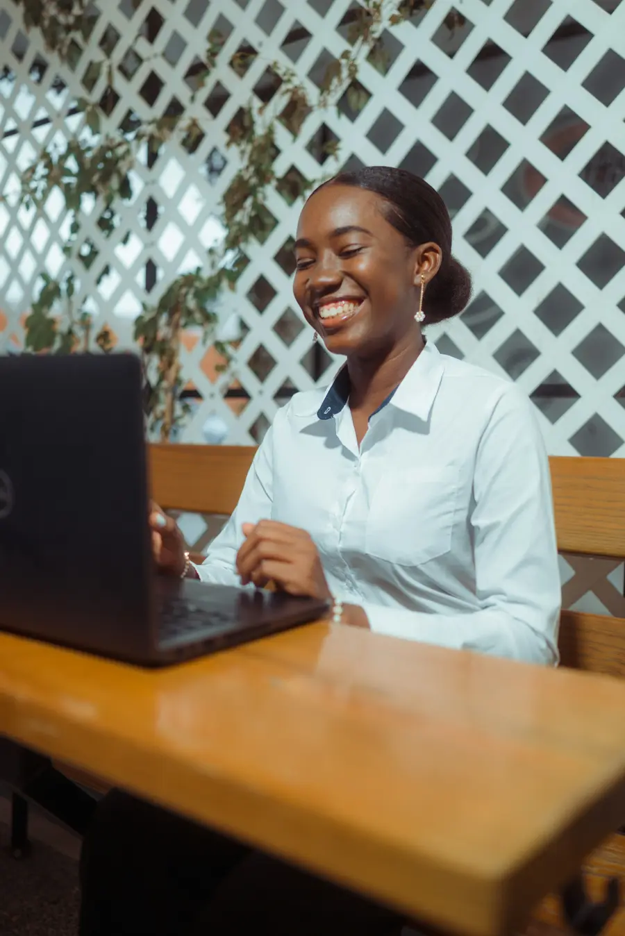 Mulher de uns 35 anos sorrindo fazendo contas no notebook em mesa de cozinha clara
