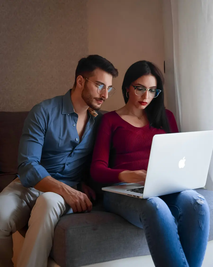 Casal sorridente analisando documentos na mesa de casa clara
