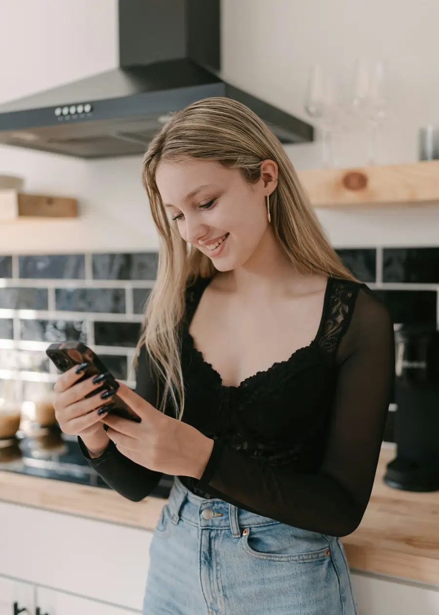 Mulher olhando o celular numa cozinha clara