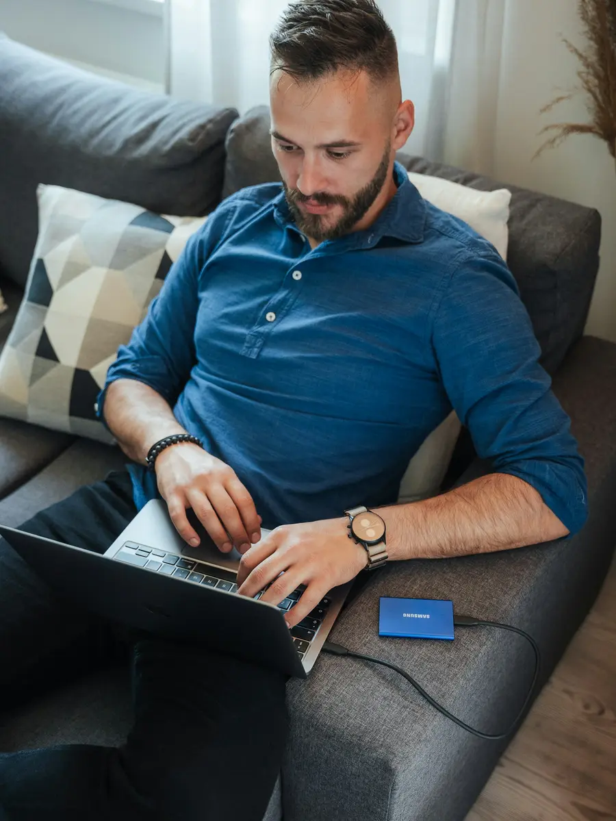 Homem usando o notebook sentado no sofá