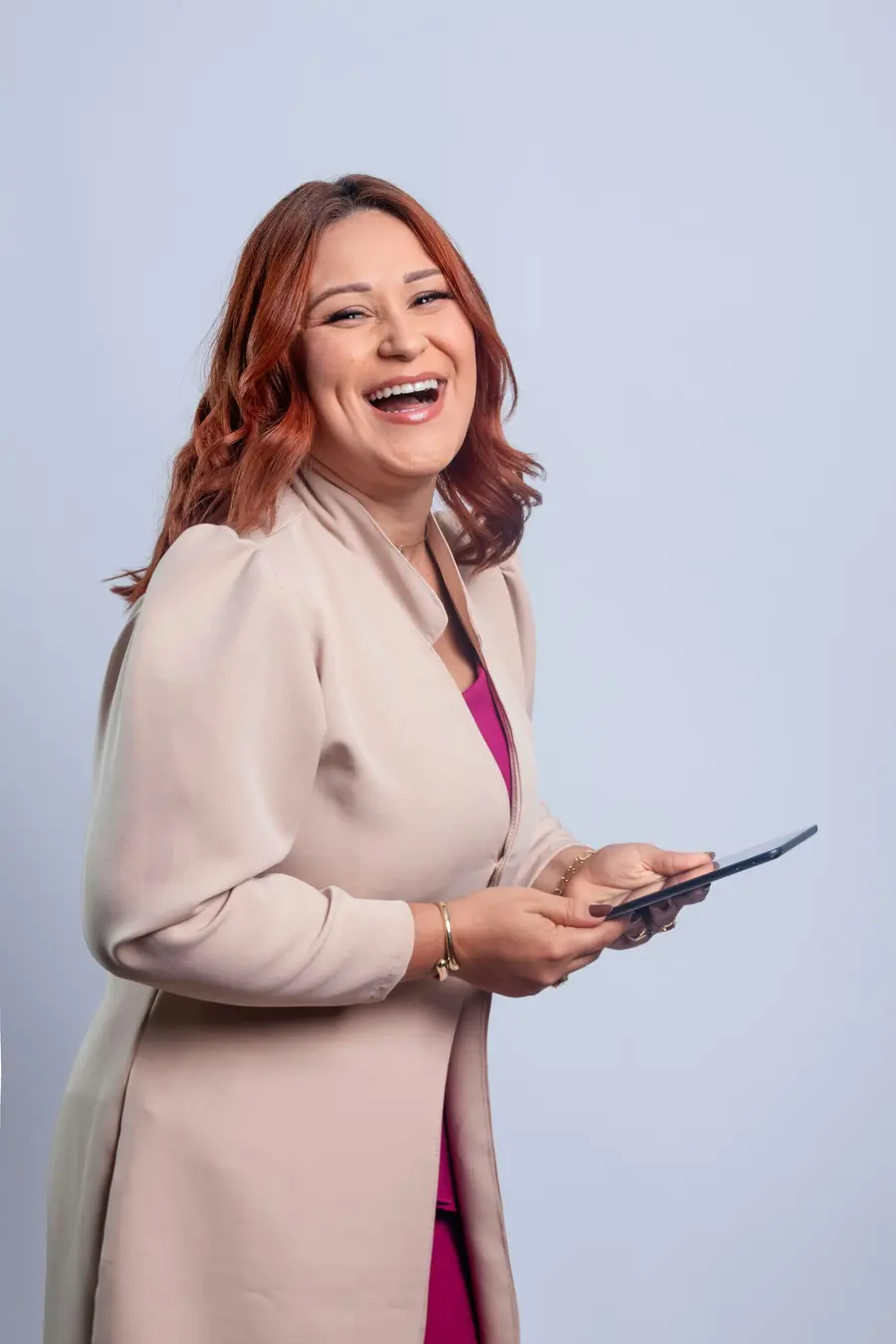 Mulher de blazer rindo enquanto segura um tablet